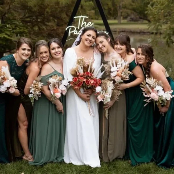 Bride and bridesmaids holding bouquets outdoors, with wedding hair and makeup by Chair'istry Salon in Wichita