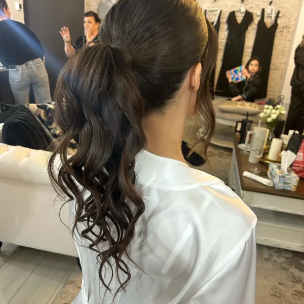 Sleek high ponytail with long voluminous curls on a client in a white robe at Chair'istry Salon