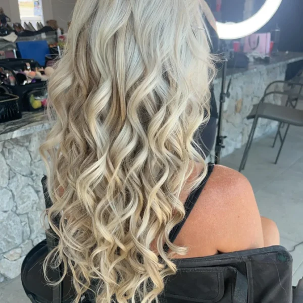 Long platinum blonde hair styled in soft, loose curls at Chair'istry Salon