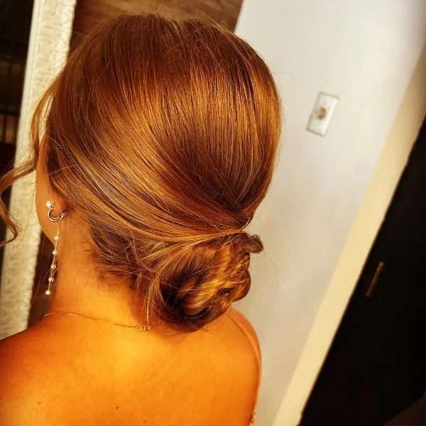 Simple, elegant sleek low bun on copper-toned hair, styled at Chair'istry Salon