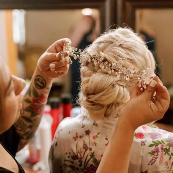 Chair'istry Salon stylist placing a crystal hair vine into a blonde bridal updo